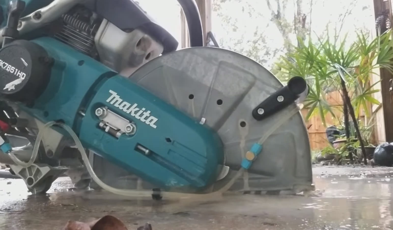 Concrete cut-off saw resting on a wet concrete work area